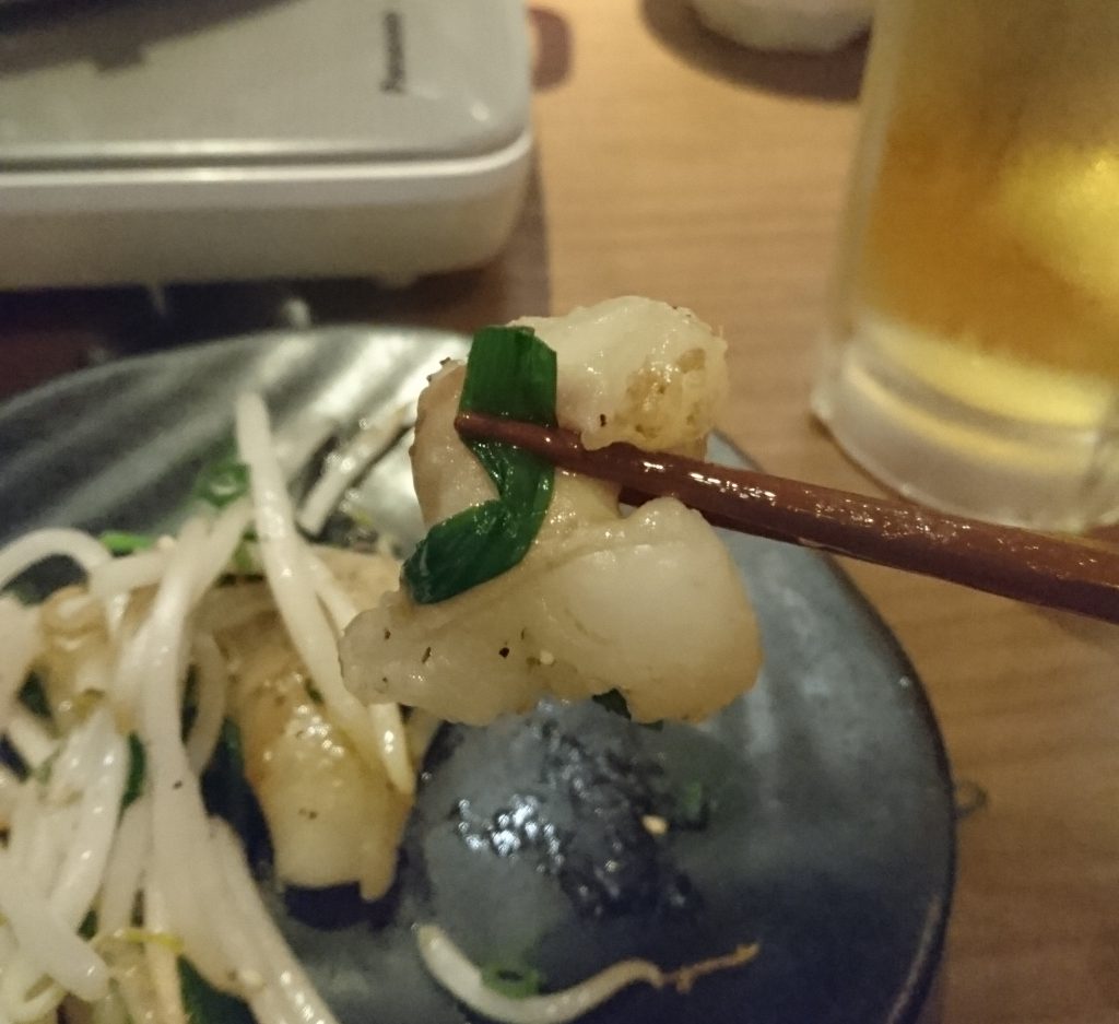 丸腸ガーリックの中にあるもつをはしで持ち上げる