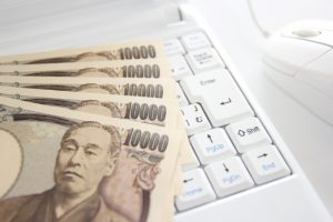 パソコンの上に複数枚の一万円札がおいてある